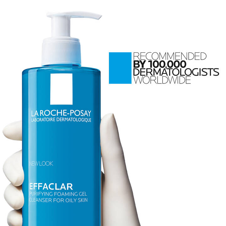 Blue bottle of La Roche-Posay Effaclar with a hand holding it, on a white background.